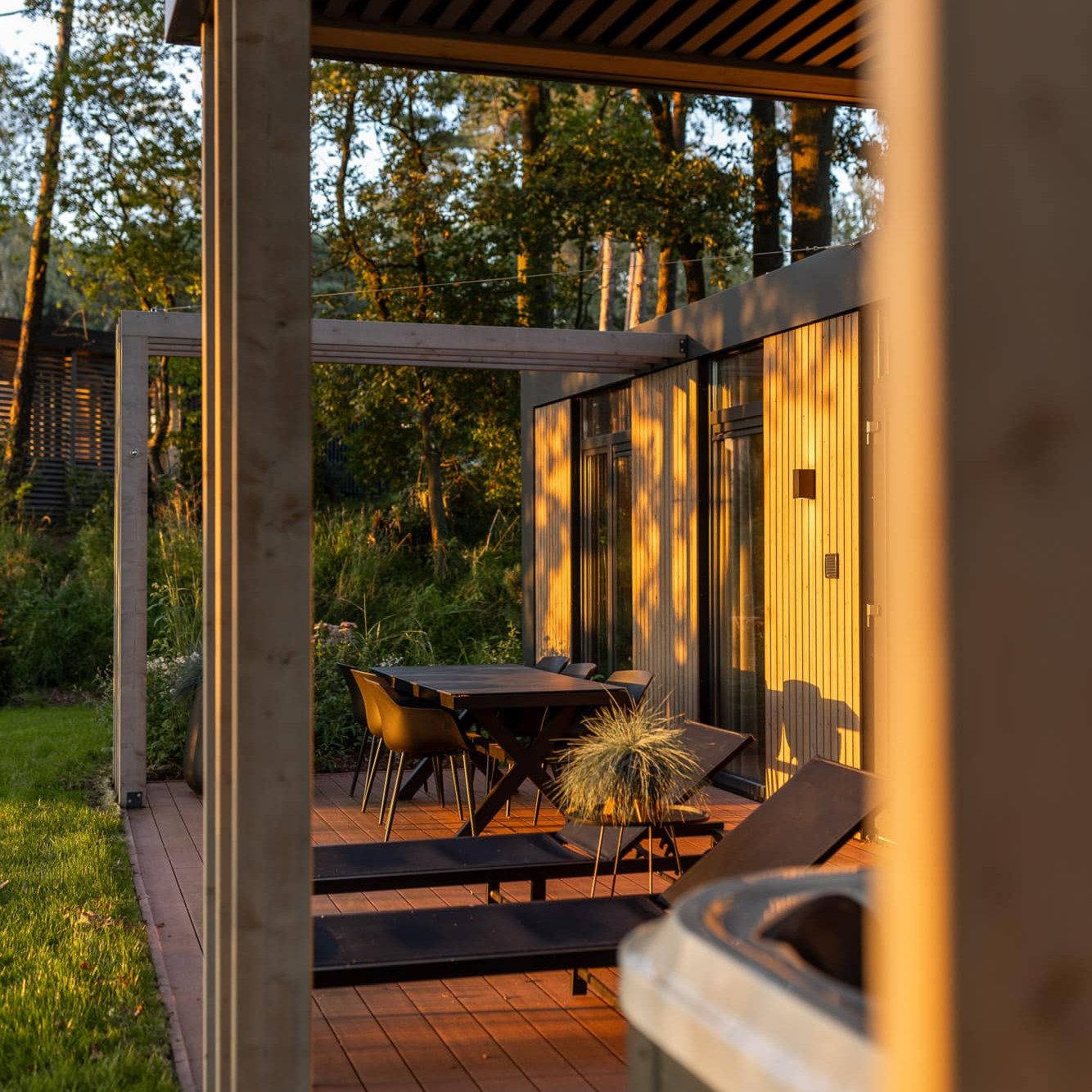 Luxe houten terras met loungestoelen en eettafel bij Panorama Lodge in gouden avondlicht