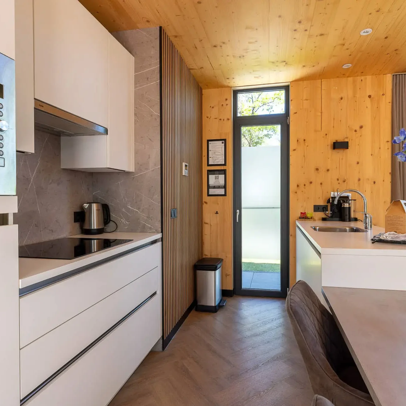 Moderne keuken in Panorama lodge met houten wanden, witte kasten en uitzicht op natuur