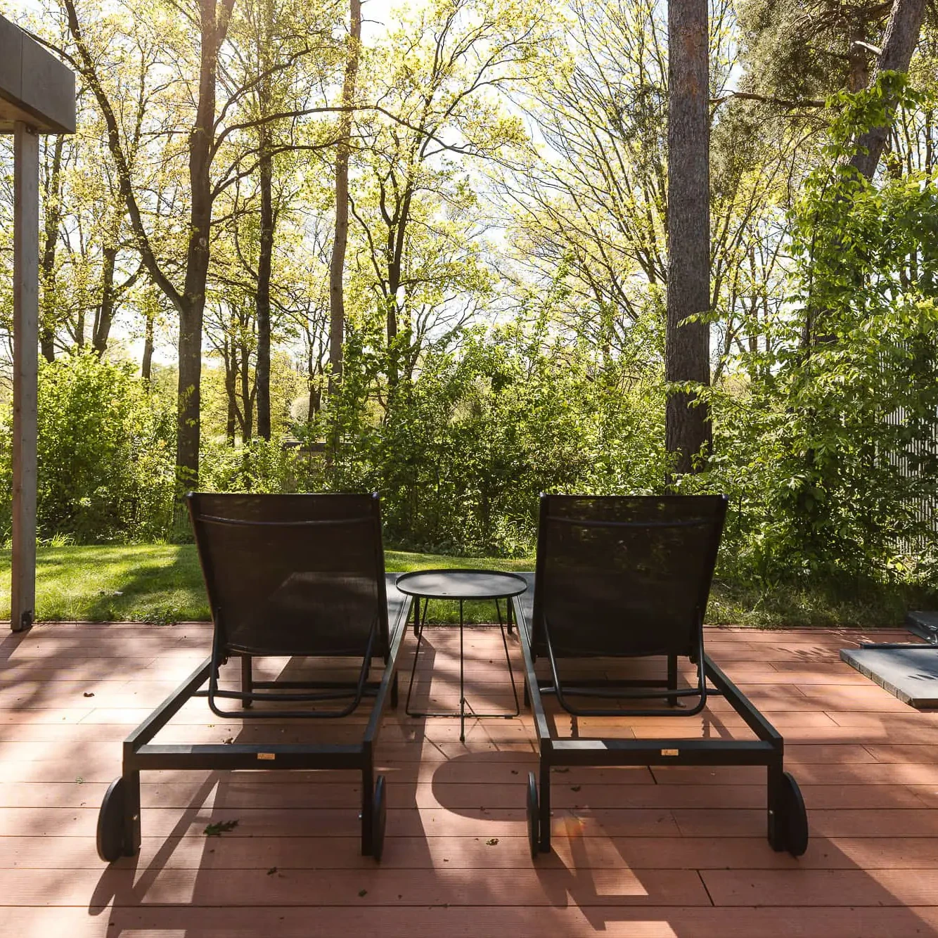 Twee ligbedden op houten terras met uitzicht op bosrijke natuur bij Zicht op Twente Lodges