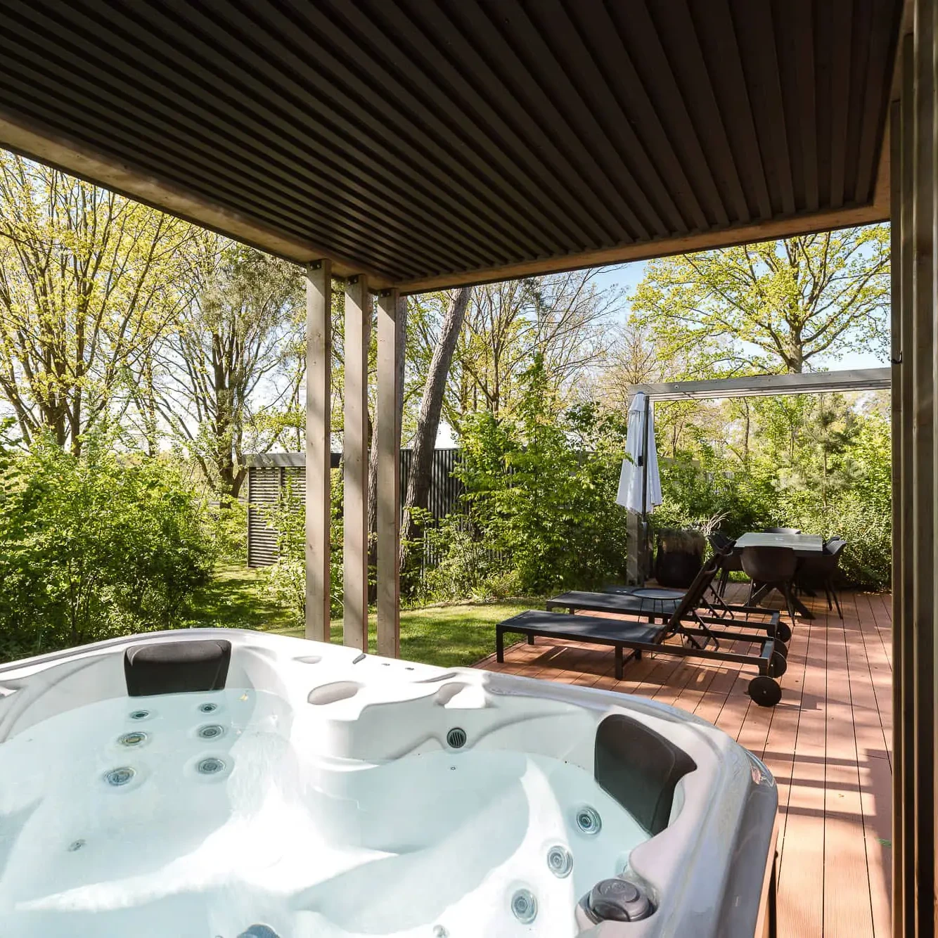 Luxe jacuzzi op houten terras met uitzicht op groene natuur bij Zicht op Twente Lodges