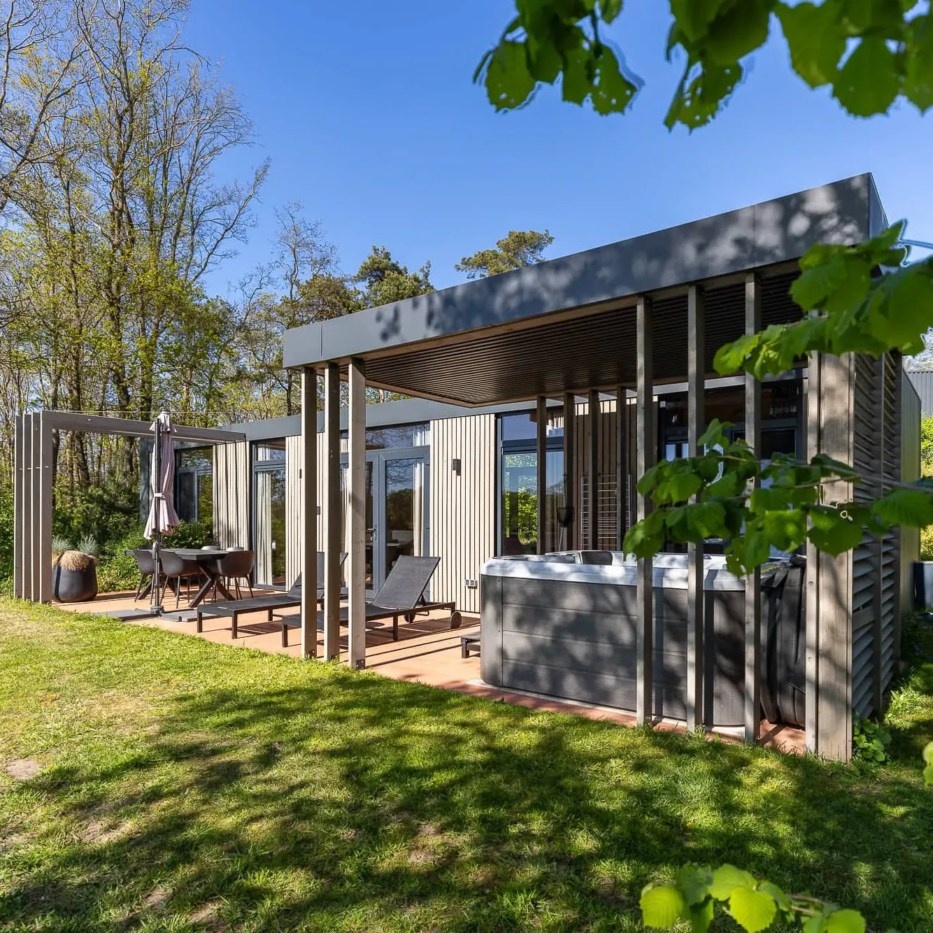 Moderne Panorama lodge met terras, ligbedden en jacuzzi in bosrijke omgeving Markelo