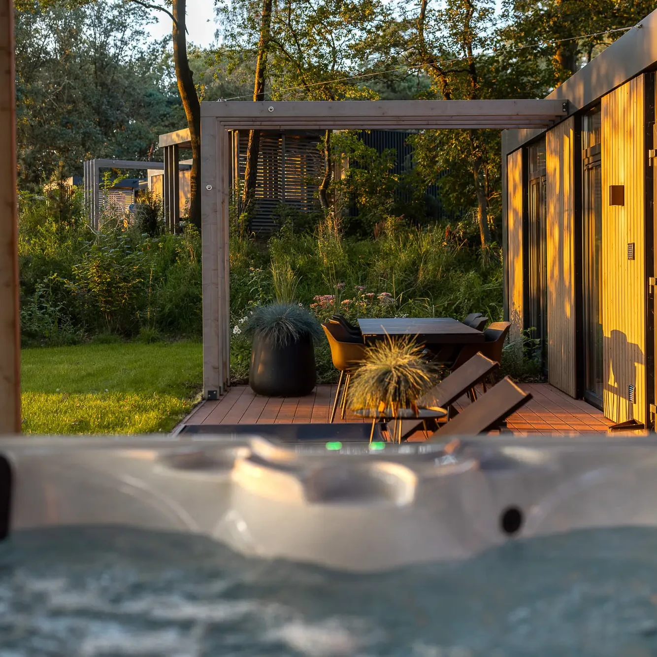Jacuzzi met uitzicht op terras en groene tuin bij luxe lodge in Markelo